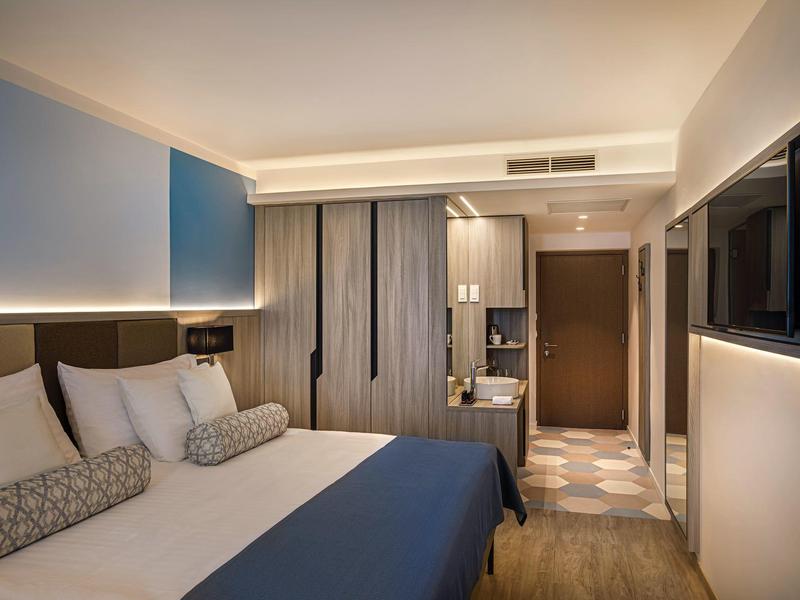 Moderně zařízený hotelový pokoj s velkou postelí, dřevěnou podlahou a skříní.