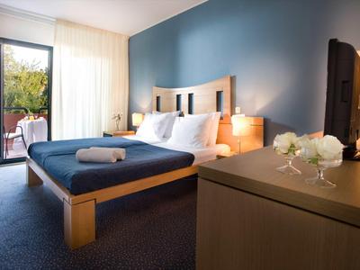 Moderne hotelkamer met tweepersoonsbed, blauwe muur en balkon toegang.