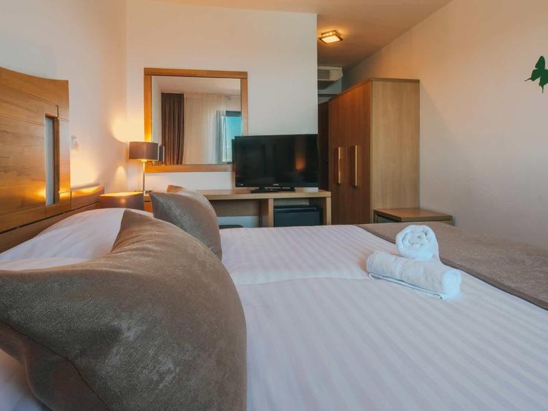 Cozy hotel room with a bed, TV, mirror, wardrobe, and butterfly wall decor.