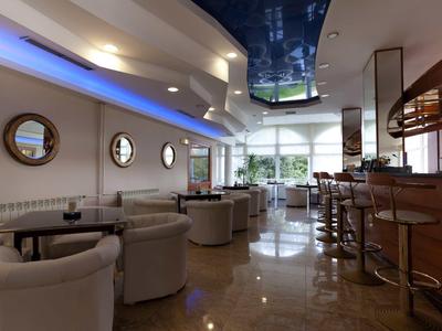 Bar moderno de hotel con sillones cómodos, espejos redondos y barra con taburetes.