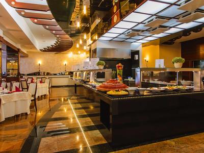 Restaurante moderno con buffet, iluminación elegante, áreas para sentarse acogedoras y ambiente cálido.