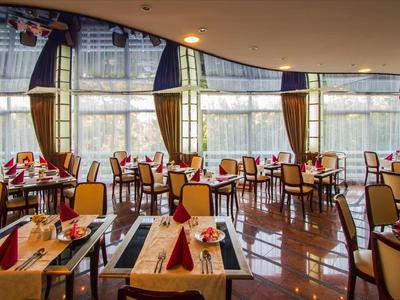 Restaurante elegante con mesas preparadas y grandes ventanales con cortinas.