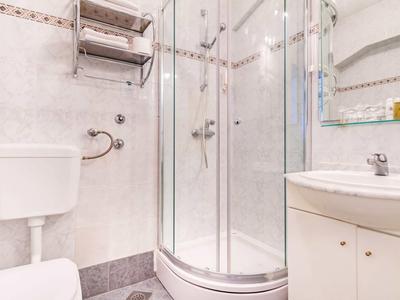 Baño compacto con ducha, inodoro y lavabo en decoración clara.