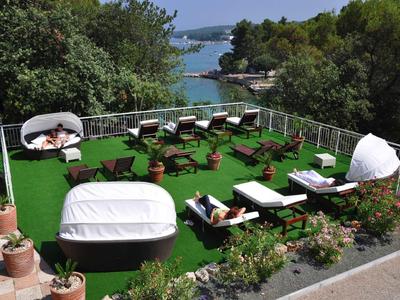 Terraza en la azotea con tumbonas y asientos rodeada de árboles con vista al mar.