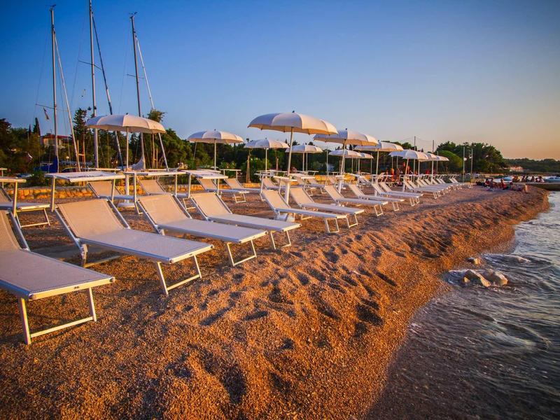 Spiaggia con lettini e ombrelloni al tramonto vicino al mare