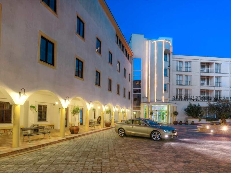 Edificio dell'hotel illuminato con auto parcheggiata nel vialetto sotto un cielo serale limpido.