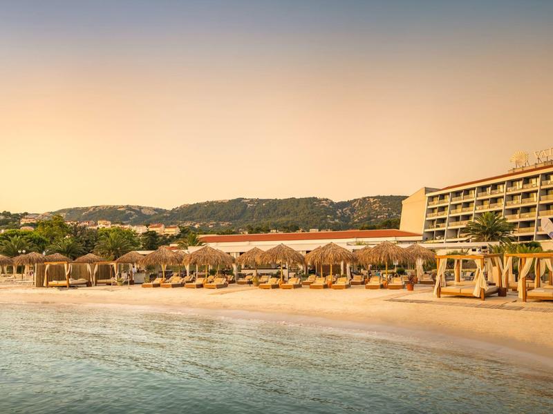 Zachód słońca na plaży z hotelem, leżakami i parasolami przy wodzie