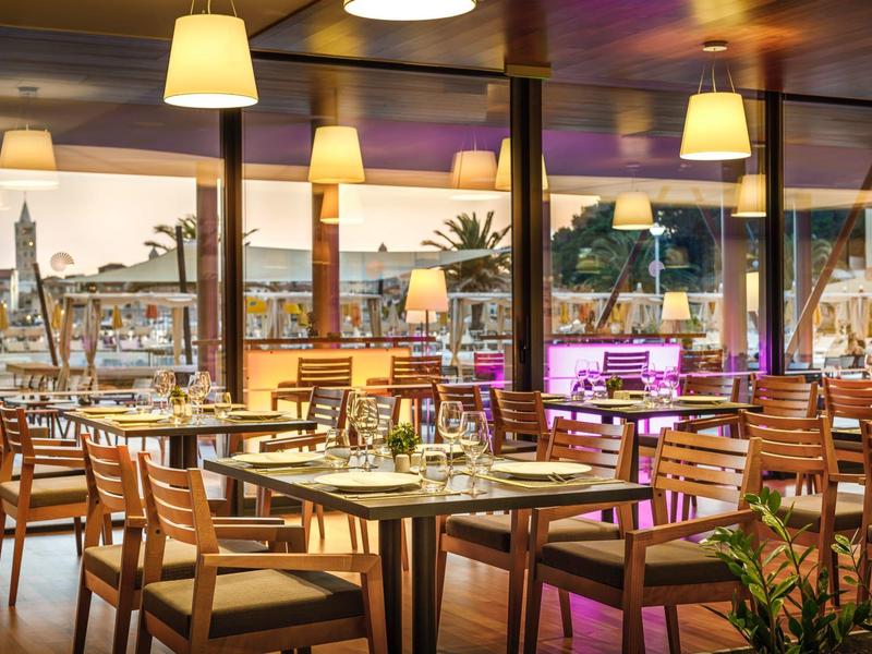 Nowoczesne wnętrze restauracji z drewnianymi stołami i krzesłami, nakrytymi i oświetlonymi.