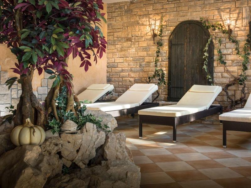 Przytulne miejsce odpoczynku z leżakami i ścianami z naturalnego kamienia w strefie spa.