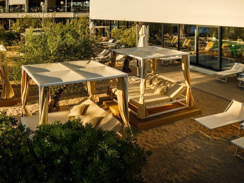 Nowoczesna strefa na zewnątrz z drewnianymi leżakami, łóżkami dziennymi i roślinami w hotelu.