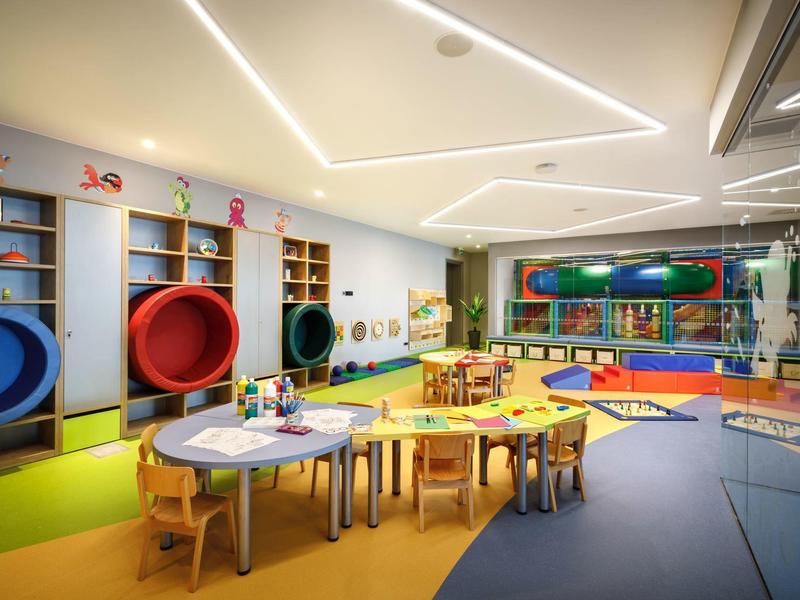 Kolorowa sala zabaw dla dzieci z stołami, krzesłami, zjeżdżalniami i zabawkami w hotelu.