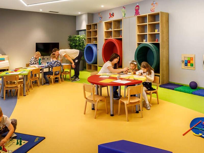 Pokój zabaw dla dzieci z kolorowymi meblami, dywanikami i zabawkami w hotelu lub ośrodku.