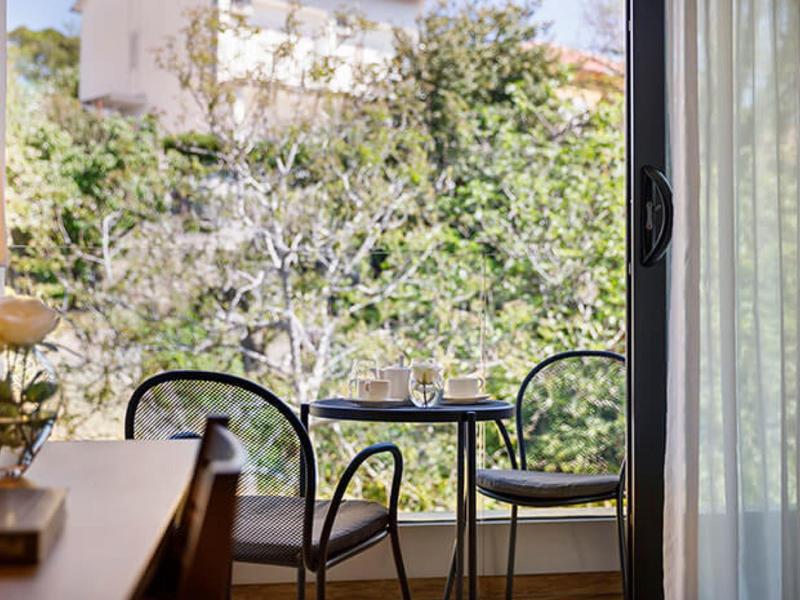 Miejsce do siedzenia z dwoma krzesłami i małym stolikiem przed oknem z widokiem na drzewa.