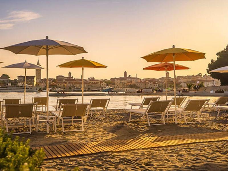 Puste leżaki z parasolami na plaży o zachodzie słońca nad morzem.