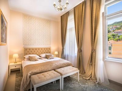 Camera accogliente con letto matrimoniale, due panchine e grandi finestre con vista.