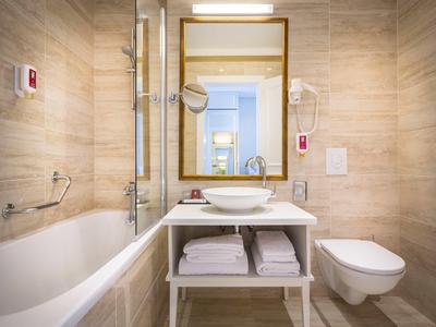 Bagno moderno con vasca, lavabo, specchio e WC in toni caldi.