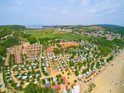 Luftaufnahme eines belebten Ferienparks mit vielen Wohnwagen und nahegelegener Sandstrand