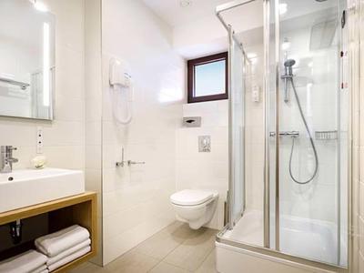 Lichte, moderne hotelbadkamer met douche, toilet, wastafel, handdoeken en föhn.