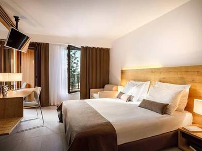 Modern hotelkamer met tweepersoonsbed, bureau en groot raam met gordijnen.