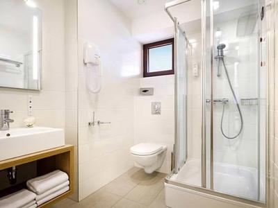 Moderne badkamer met douche, toilet, wastafel en handdoeken in een lichte ruimte.