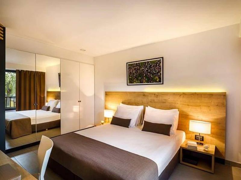 Moderne hotelkamer met groot bed, houten accenten en warme verlichting.