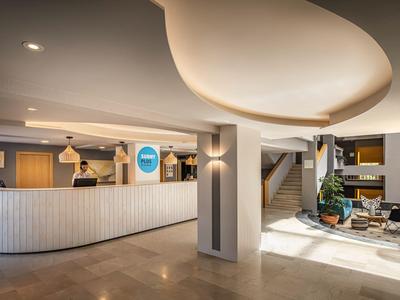 Hall d'accueil d'hôtel moderne avec comptoir incurvé, réceptionnistes et espace d'attente.