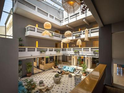 Atrium d'hôtel lumineux avec plusieurs étages et des espaces de détente autour d'une fontaine.