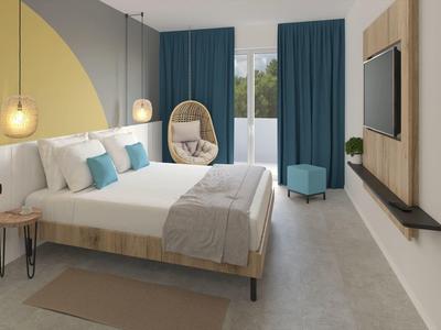 Moderní hotelový pokoj s manželskou postelí, závěsným křeslem a televizí na stěně.