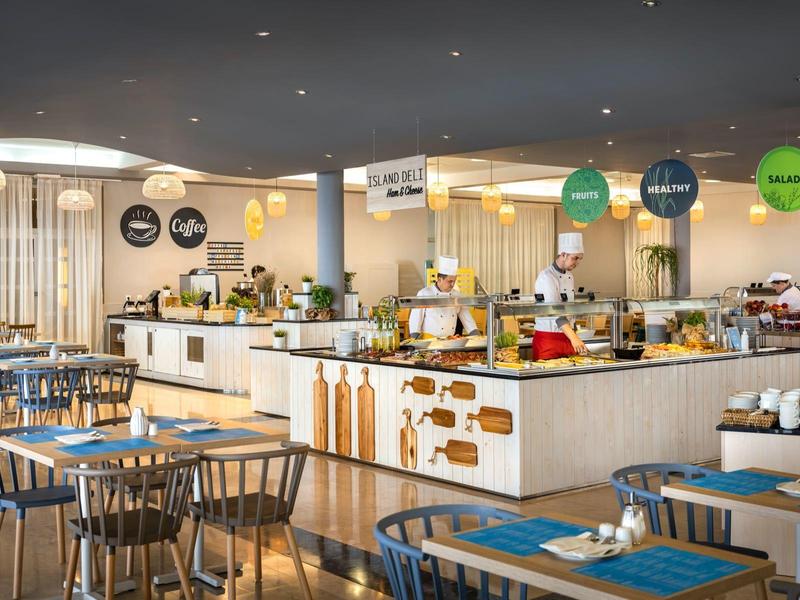 Moderní hotelová restaurace s bohatým bufetem a stylovým dřevěným nábytkem.