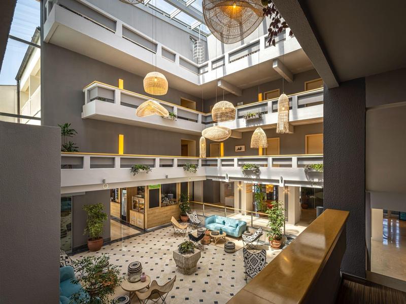 Vnitřní dvůr moderního hotelu se sezením a přirozeným světlem shora.