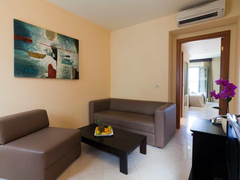 Camera d'albergo moderna con divani comodi, tavolino e un dipinto colorato sulla parete.