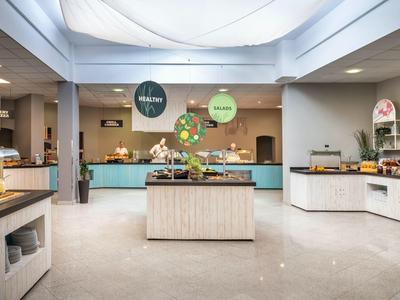 Salle de petit-déjeuner moderne avec buffet et comptoirs en bois clair dans un hôtel.