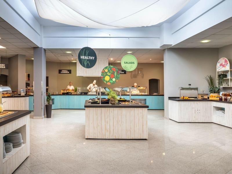 Salle de petit-déjeuner moderne avec buffet et comptoirs en bois clair dans un hôtel.