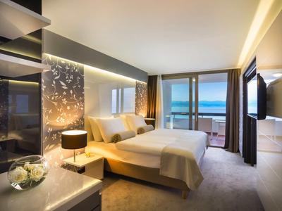 Chambre d'hôtel moderne avec grand lit et balcon avec vue sur la mer.