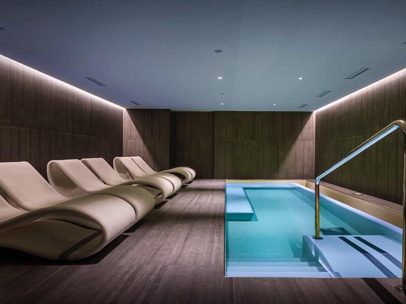 Modern indoor pool with comfortable lounge chairs and indirect lighting in a relaxing atmosphere.