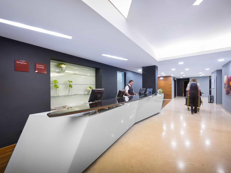Modern hotel lobby reception with curved white front desk and staff.