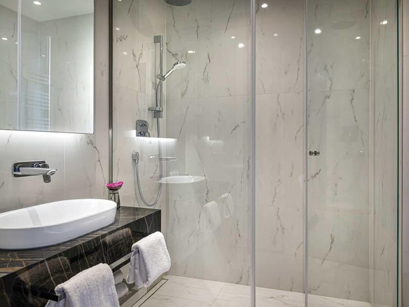 Modern bathroom with sink, illuminated mirror, and walk-in glass shower.