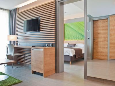 Modern hotelkamer met houten accenten, bureau, tv en uitzicht op de slaapkamer.