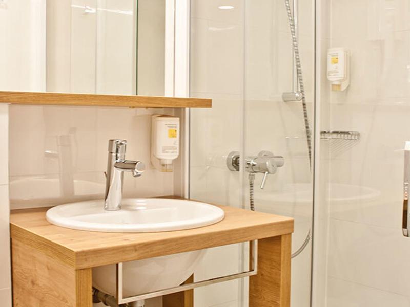 Kleine helle Badezimmer mit Holzwaschtisch und moderner Glasdusche in Beige- und Holztönen.