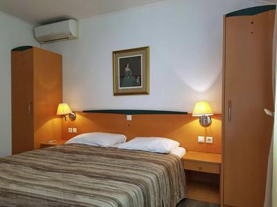 Ein einfaches Hotelzimmer mit einem Doppelbett, zwei Nachttischen und Schränken.