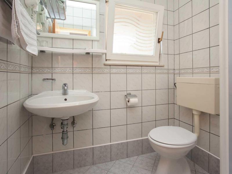 Piccolo bagno con WC, lavandino e finestra con persiana.