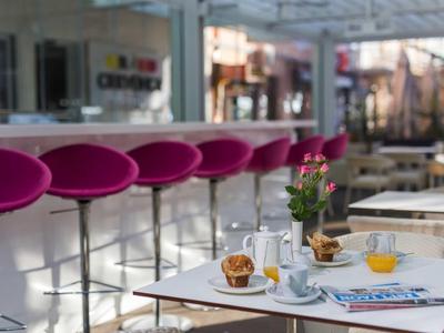 Une table avec petit-déjeuner et fleurs devant une rangée de tabourets rouges dans un café.