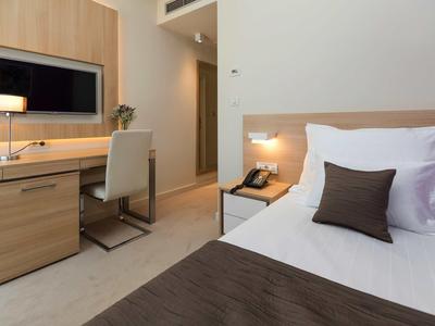 Chambre d'hôtel moderne avec bureau, chaise, télévision et lit avec coussins.