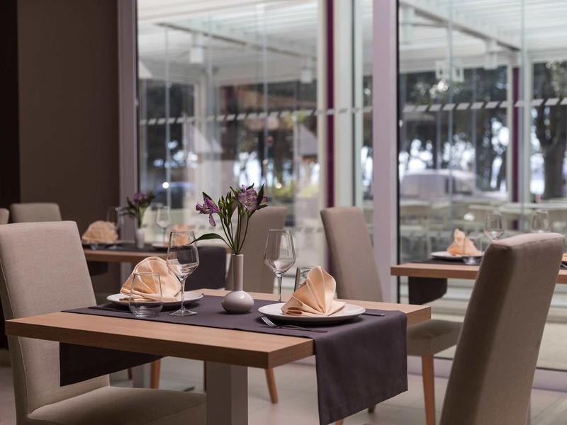 Elegant restaurant with set tables and modern interior next to large windows.