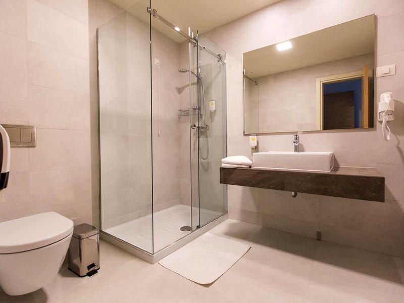 Modern hotel bathroom with walk-in shower, toilet, and large mirror.