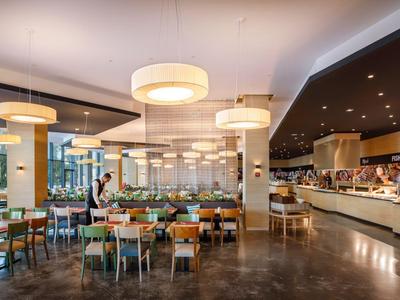 Restaurante moderno de hotel con mesas preparadas y área de buffet con luz cálida.