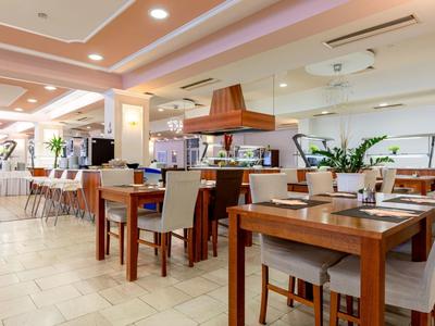 Helles Hotelrestaurant mit Holztischen, bequemen Stühlen und moderner Innenausstattung.