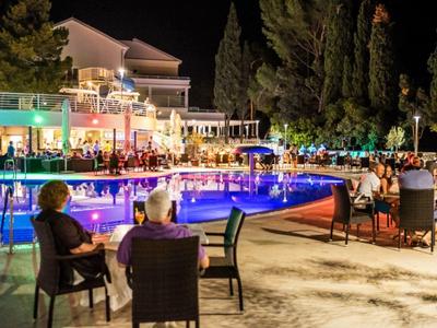 Abendliche Poolbar mit Gästen in entspannter Hotelatmosphäre bei Nacht.