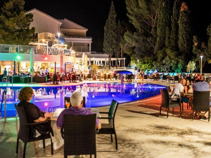 Abendliche Poolbar mit Gästen in entspannter Hotelatmosphäre bei Nacht.