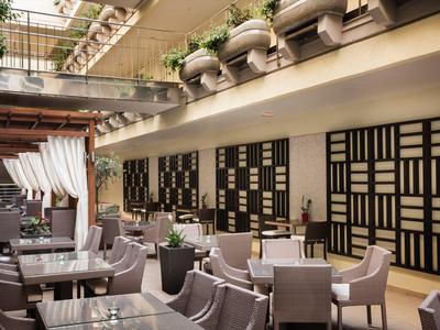 Moderner Innenhof mit Glasdach, gemütlichen Sitzgelegenheiten und dekorativen schwarz-weißen Wandpanelen.